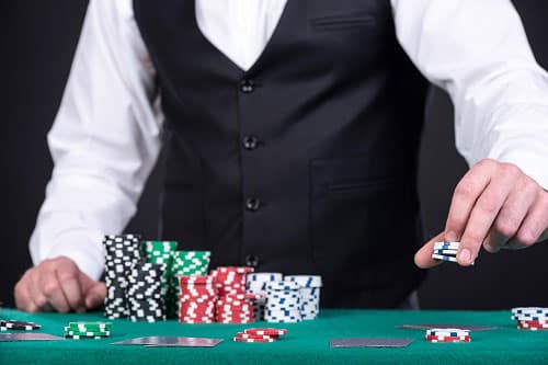 Casino dealer stacking chips on his black jack table