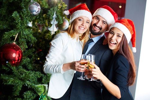 Work staff cheering drinks on a Christmas party while wearing Santa Claus hats