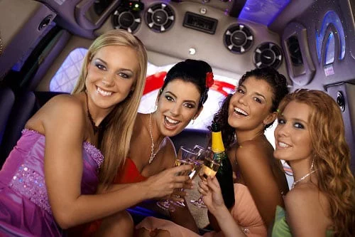 Girls out on a hens party, having a celebration drink in the back of a stretch limousine