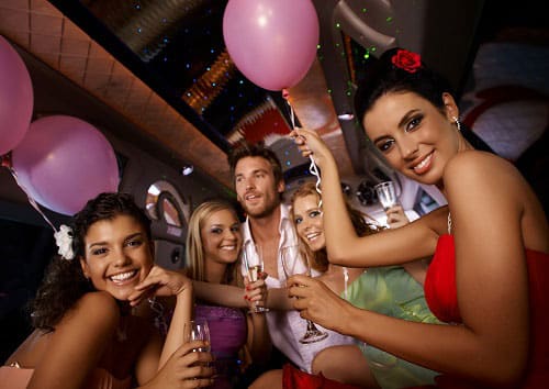 Group having a party with balloons and drinks in the back of a limo